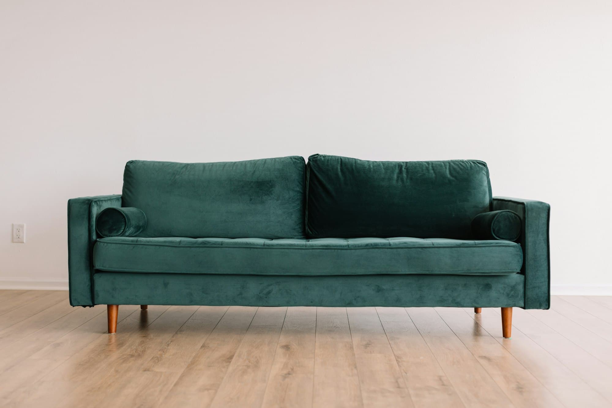 A green velvet sofa in a bright, minimal living room